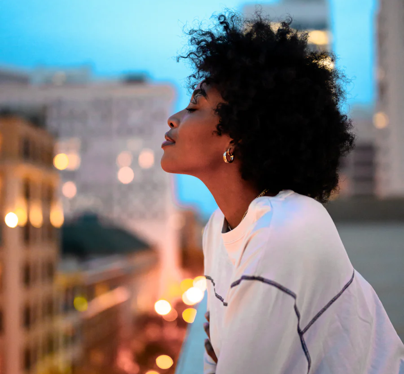 Woman with eyes close on a building balcony